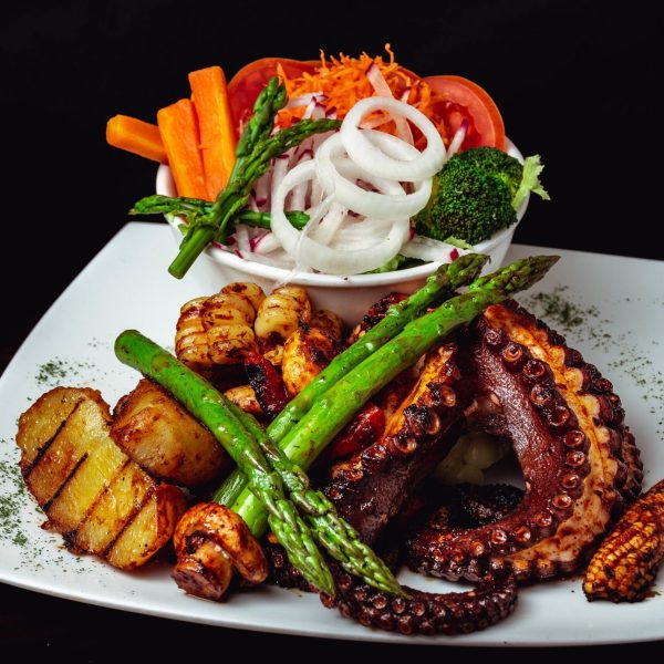 A closeup shot of a delicious roasted octopus dish with roasted asparagus, and veggies