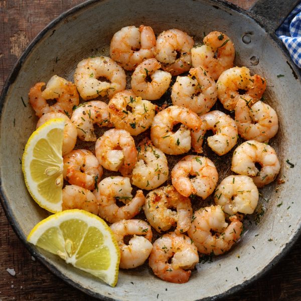Tasty appetizing fried shrimps on pan on dark stone background. Top View.